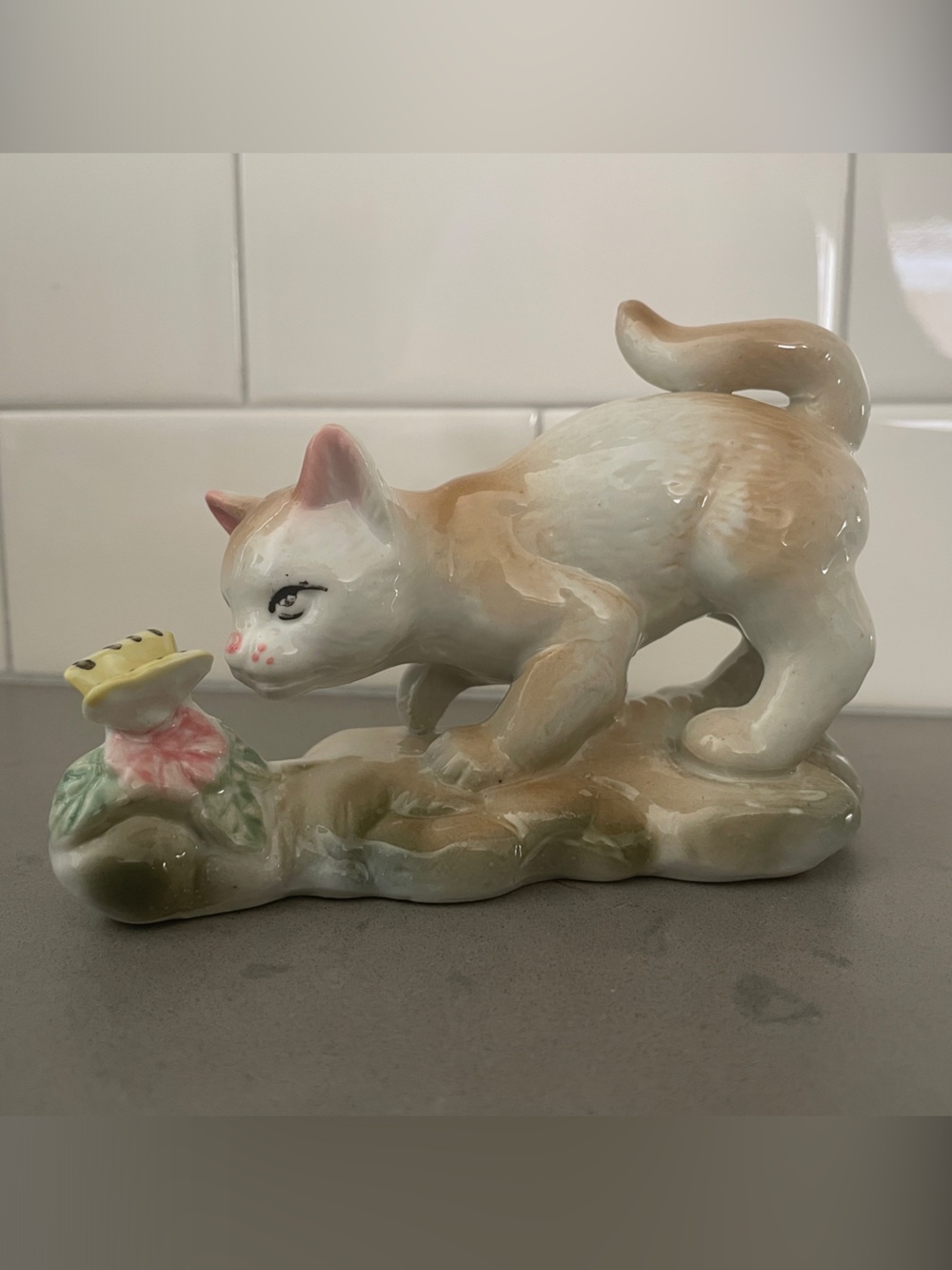 Vintage porcelain cat figurine playing with a butterfly.
